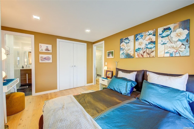 bedroom with light wood-type flooring, connected bathroom, and a closet