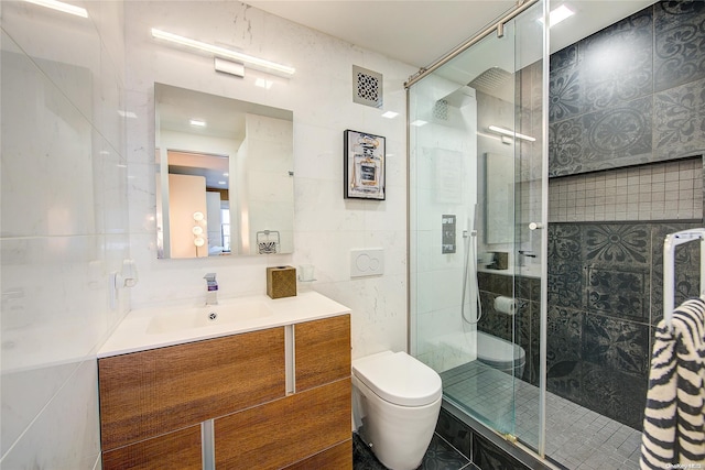 bathroom with vanity, toilet, tile walls, and a shower with shower door