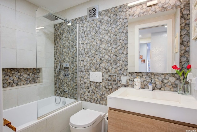 full bathroom featuring vanity, toilet, tiled shower / bath, and tile walls