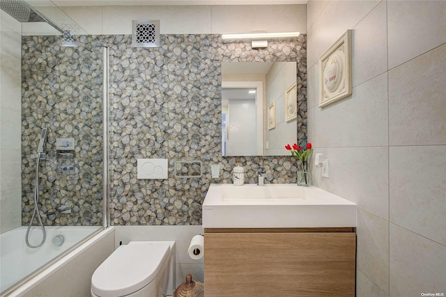 full bathroom with  shower combination, vanity, tile walls, and toilet