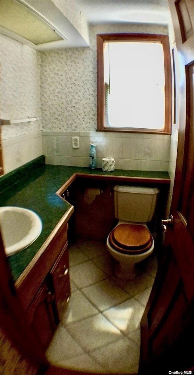 bathroom with vanity, toilet, and tile walls