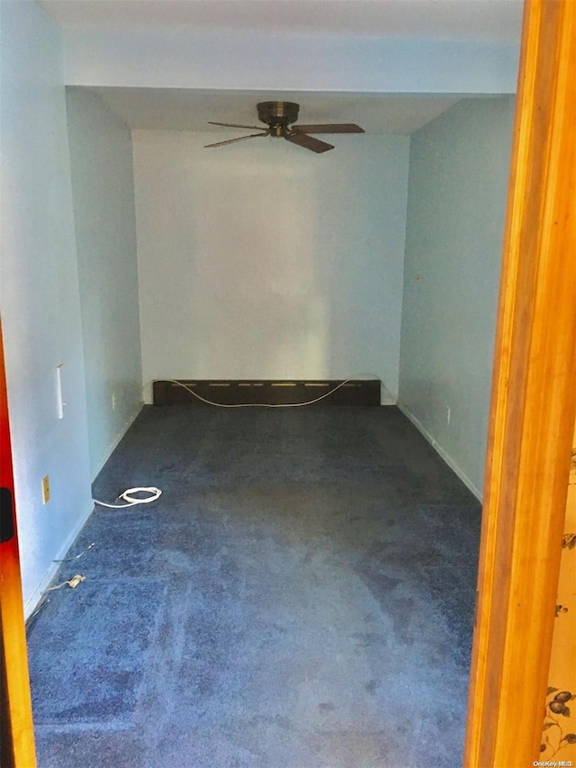 unfurnished room featuring ceiling fan and dark colored carpet