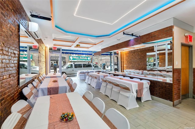 dining room featuring a tray ceiling, a wall mounted AC, brick wall, and wood-type flooring