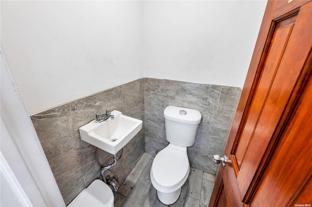 bathroom featuring hardwood / wood-style flooring, tile walls, and toilet