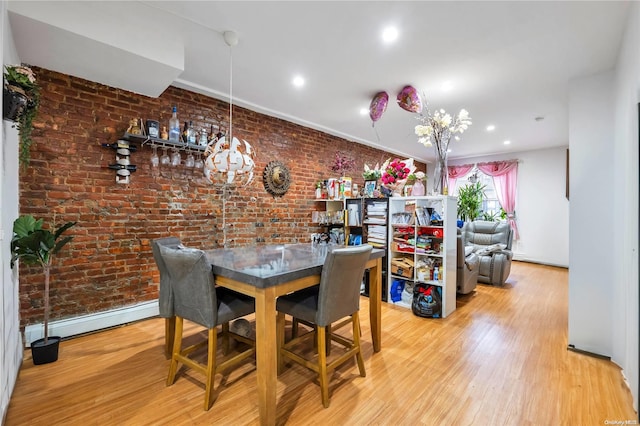 dining room with a baseboard radiator, light hardwood / wood-style floors, and brick wall