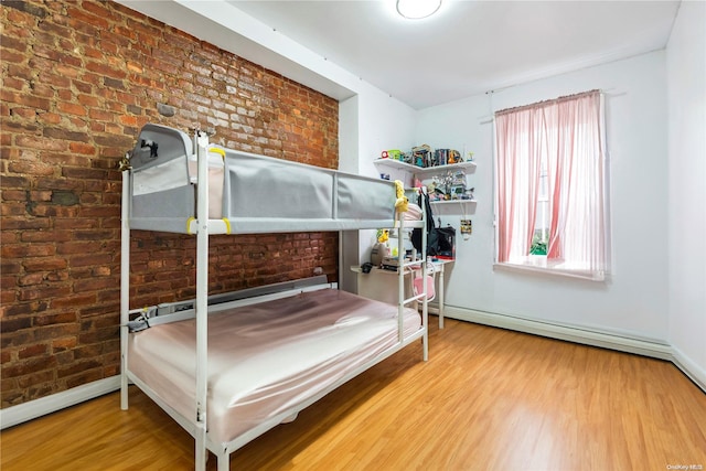 bedroom with brick wall, a baseboard radiator, and hardwood / wood-style flooring