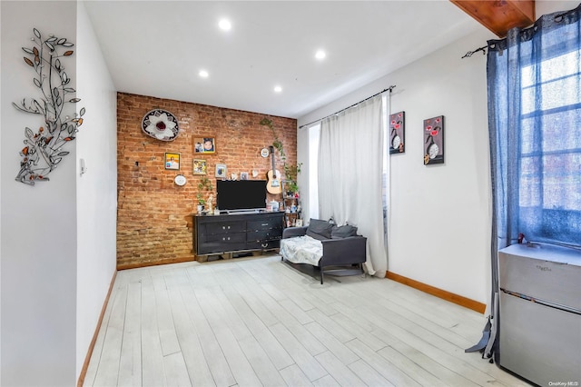 living area with light hardwood / wood-style floors and brick wall