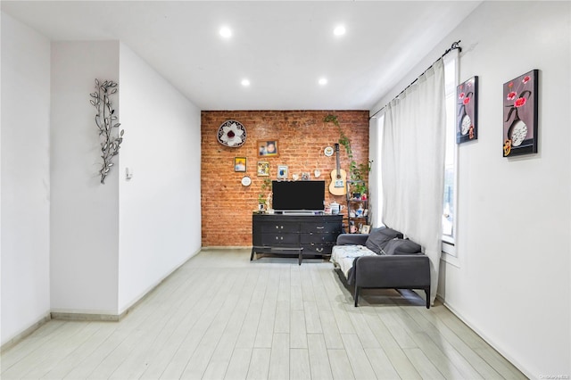 sitting room featuring light hardwood / wood-style floors and brick wall