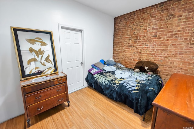 bedroom featuring light hardwood / wood-style floors and brick wall