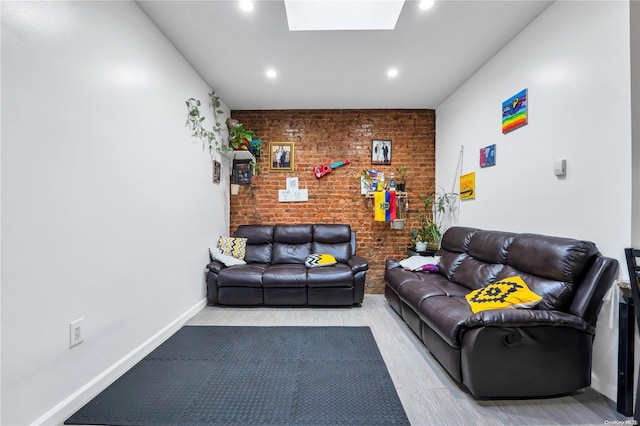 living room featuring a skylight, light hardwood / wood-style flooring, and brick wall