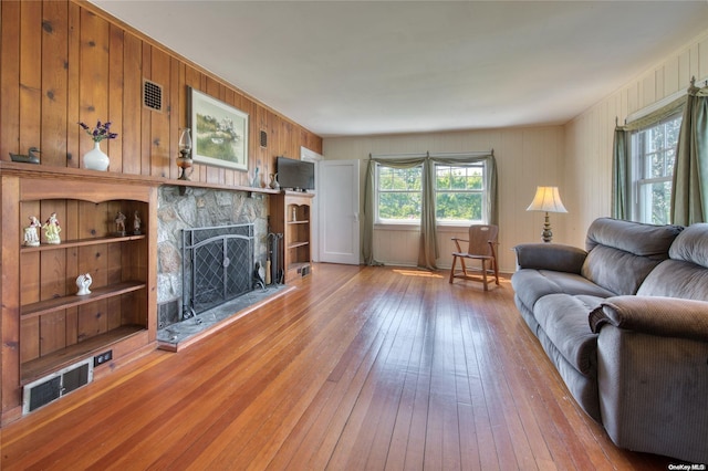 living room with wood walls, a fireplace, and wood-type flooring