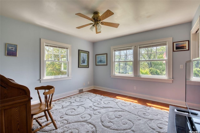 living area with light wood-type flooring, ceiling fan, and a healthy amount of sunlight