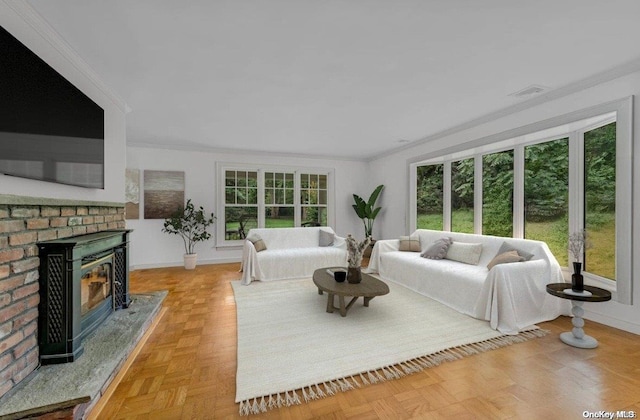 living room with a brick fireplace, a wealth of natural light, ornamental molding, and light parquet flooring