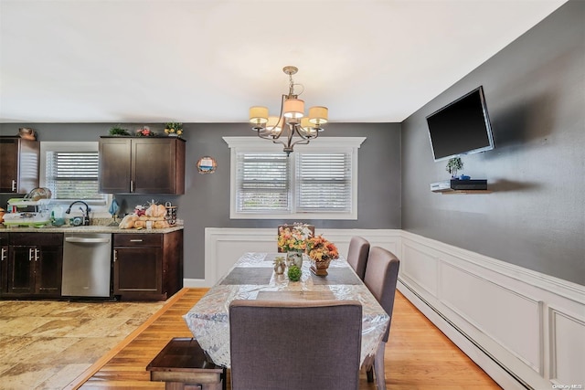 dining area with baseboard heating, light hardwood / wood-style flooring, and a notable chandelier