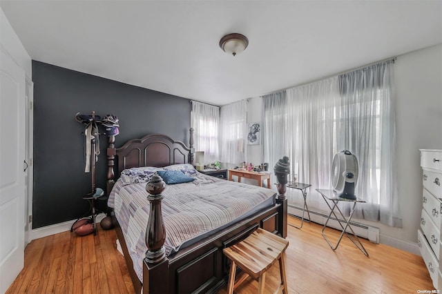 bedroom featuring a baseboard heating unit and light hardwood / wood-style flooring