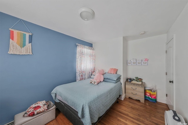 bedroom with baseboard heating and wood-type flooring