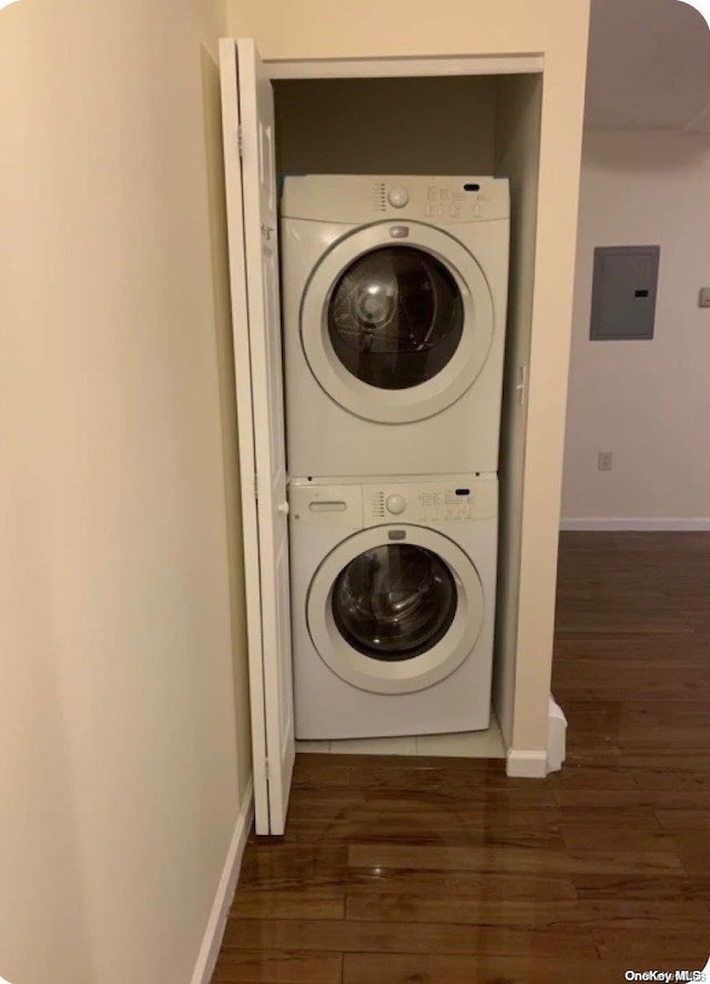 laundry area with dark hardwood / wood-style flooring, electric panel, and stacked washer / drying machine