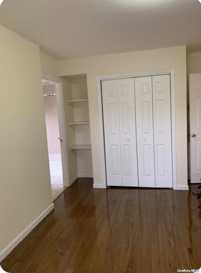 unfurnished bedroom with a closet and dark hardwood / wood-style flooring