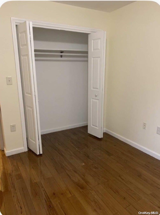 unfurnished bedroom with dark wood-type flooring and a closet