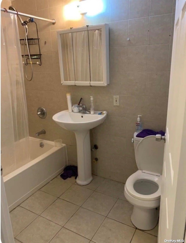 bathroom with toilet, shower / tub combo, tile patterned floors, and tile walls