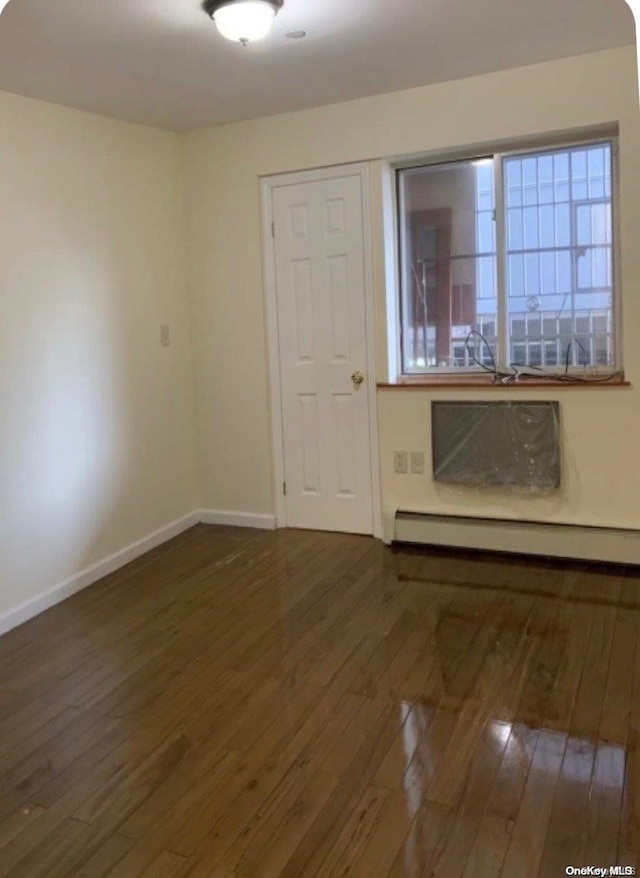 empty room with dark hardwood / wood-style floors and a baseboard radiator