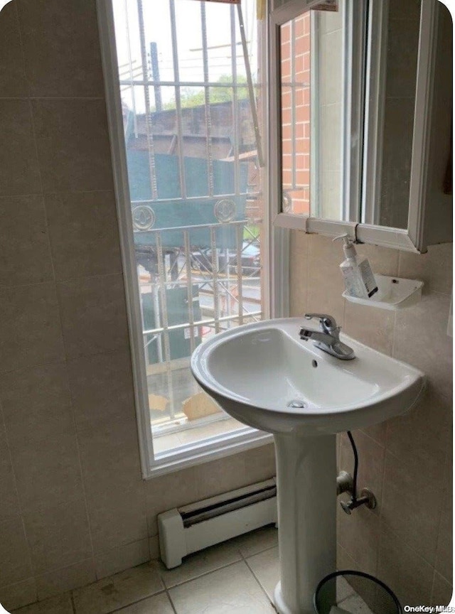 bathroom featuring tile patterned floors, plenty of natural light, tile walls, and a baseboard heating unit