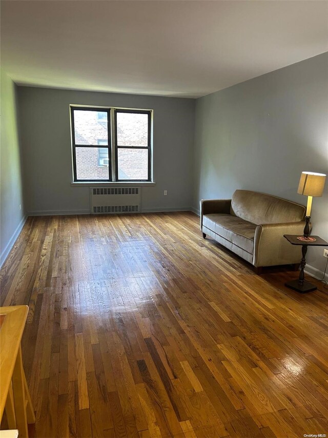 unfurnished living room featuring radiator heating unit and wood-type flooring