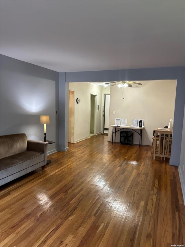 living room featuring ceiling fan and dark wood-type flooring