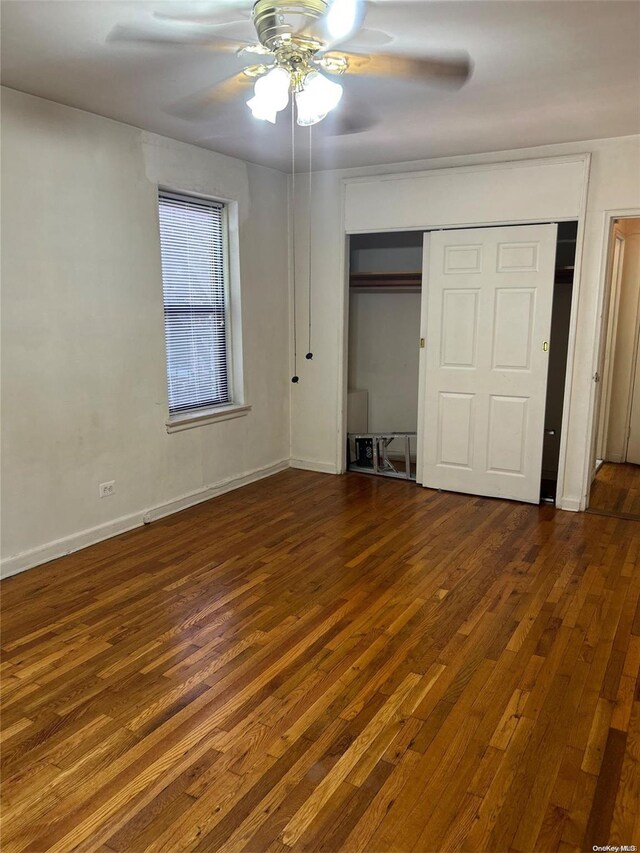 unfurnished bedroom with ceiling fan, a closet, and dark wood-type flooring