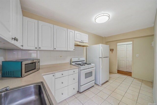 kitchen with white cabinetry, sink, tasteful backsplash, white appliances, and light tile patterned flooring