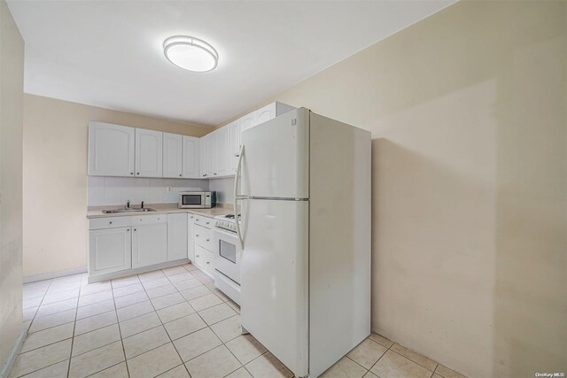 kitchen featuring light tile patterned floors, white appliances, white cabinetry, and sink