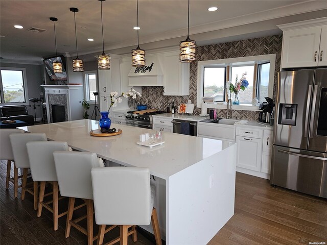 47 Pershing Ave, Babylon, NY 11702 - kitchen featuring stainless steel appliances, dark wood-style floors, a center island, white cabinetry, and ornamental molding