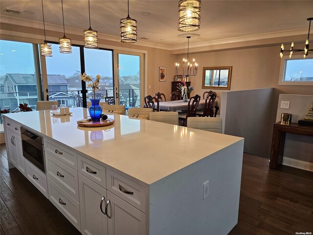 47 Pershing Ave, Babylon, NY 11702 - kitchen featuring dark wood finished floors, a chandelier, stainless steel microwave, and white cabinetry