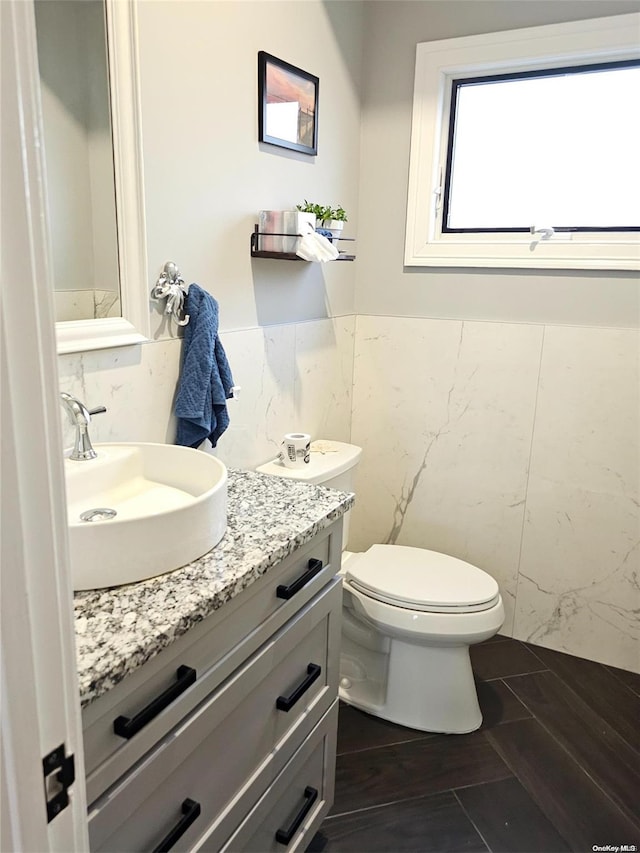 bathroom with hardwood / wood-style floors, vanity, tile walls, and toilet