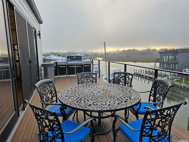 balcony at dusk with grilling area and a water view