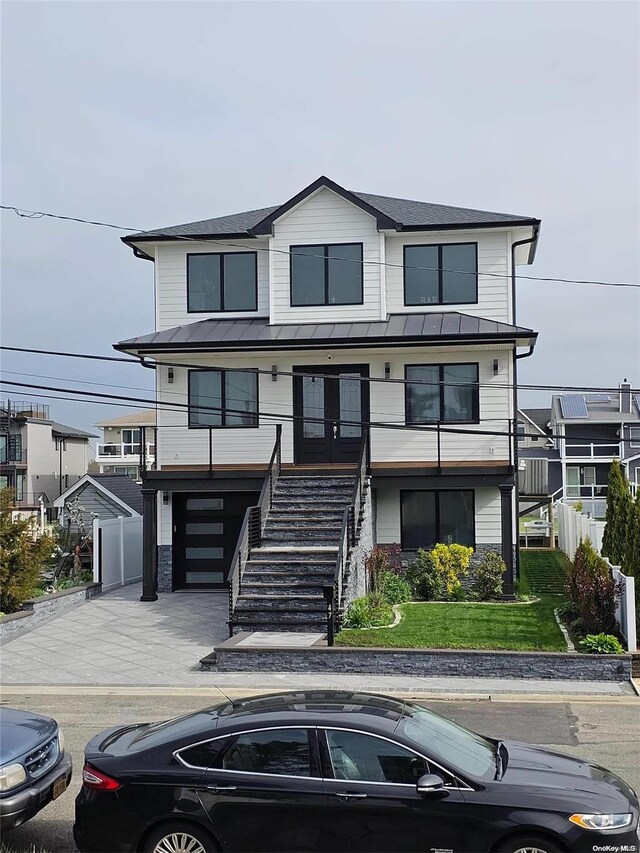 47 Pershing Ave, Babylon, NY 11702 - view of front of property with a standing seam roof, stairs, a garage, metal roof, and concrete driveway