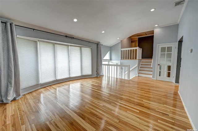 empty room with lofted ceiling, ornamental molding, and light hardwood / wood-style floors