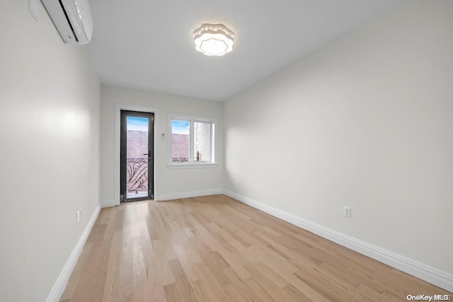 spare room with light wood-type flooring and a wall unit AC