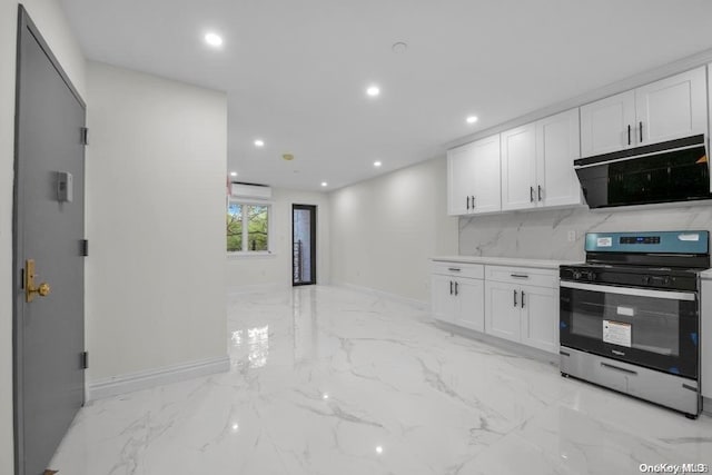 kitchen with white cabinets, backsplash, stainless steel stove, and a wall mounted AC