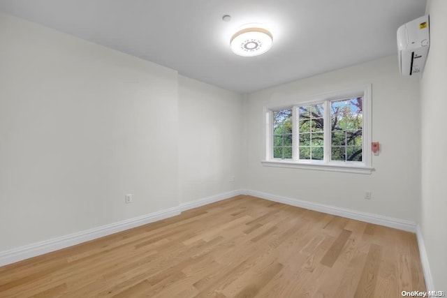 empty room featuring a wall mounted air conditioner and light wood-type flooring