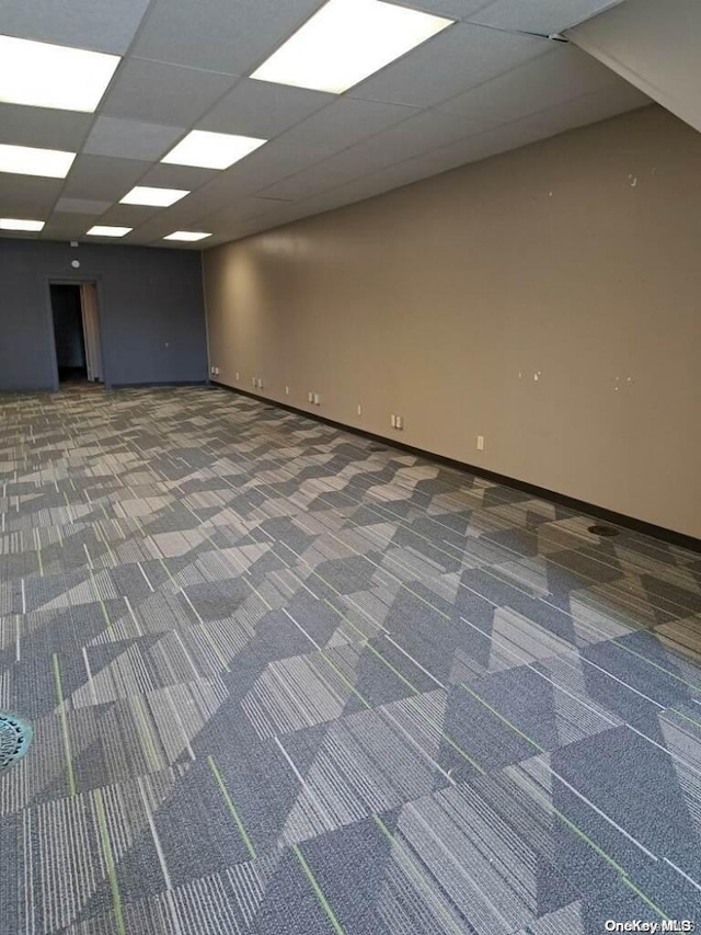 unfurnished room with a drop ceiling and dark carpet