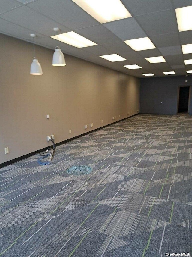 unfurnished room featuring a paneled ceiling and dark carpet