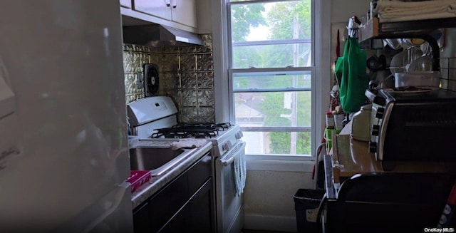 kitchen featuring white gas range oven and stainless steel fridge