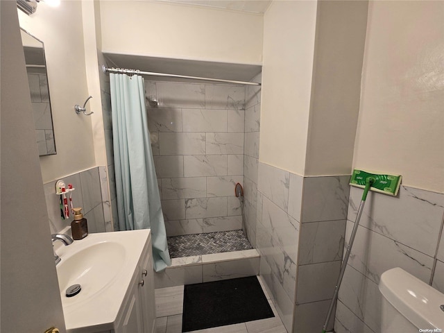 bathroom with toilet, curtained shower, tile walls, and vanity