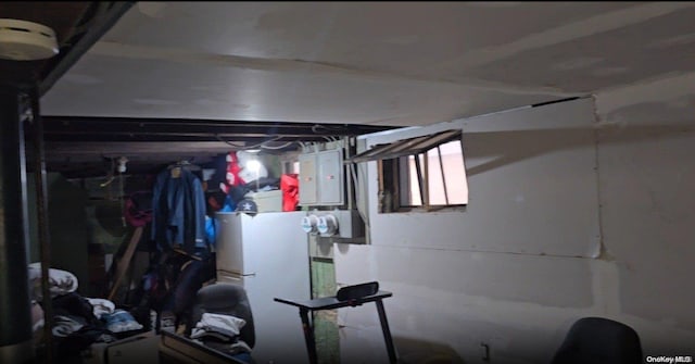 basement featuring electric panel and white fridge