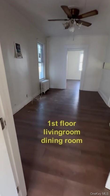 unfurnished room featuring radiator, ceiling fan, and dark wood-type flooring