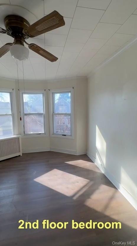 empty room with radiator, wood-type flooring, and ceiling fan