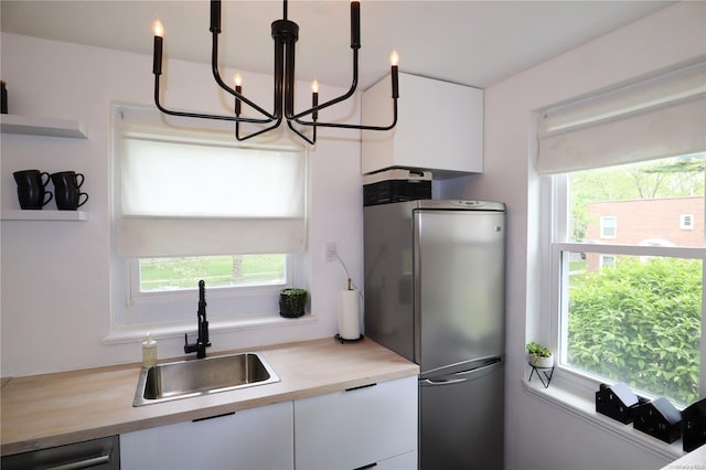 kitchen with white cabinetry, hanging light fixtures, a healthy amount of sunlight, and sink