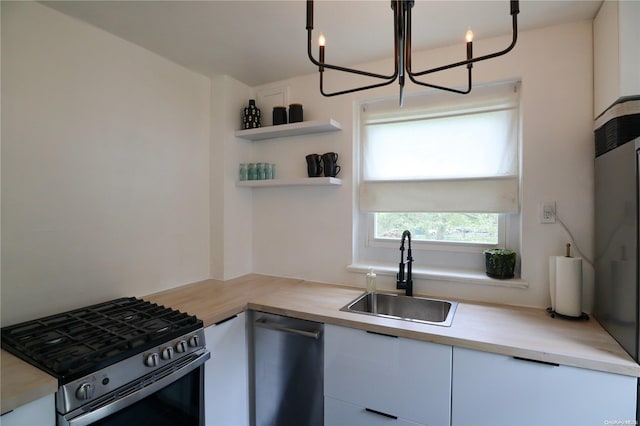 kitchen featuring white cabinets, appliances with stainless steel finishes, butcher block countertops, and sink