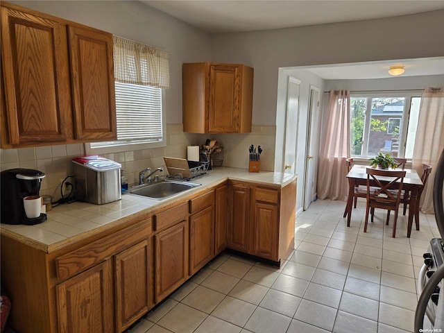 kitchen featuring tile countertops, sink, decorative backsplash, light tile patterned floors, and stainless steel range